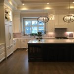 Transitional kitchen with custom cabinets, full overlay white perimeter cabinets and dark island.